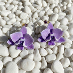 Purple orchid earrings on white pebbles