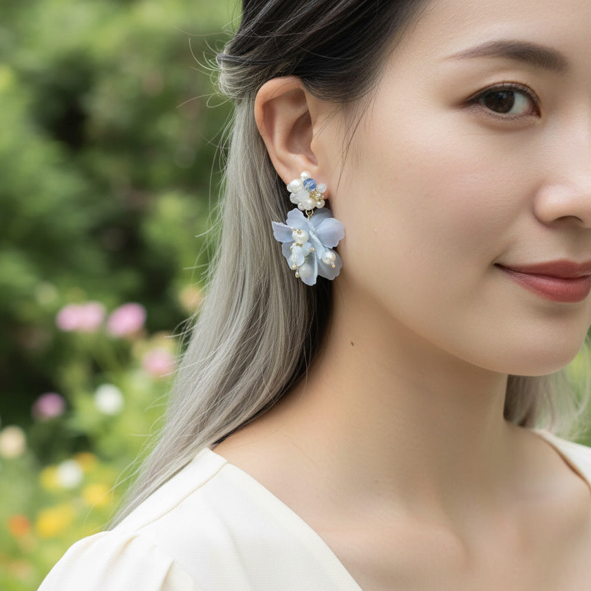 Woman wearing floral earrings with a blurred garden background