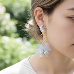 Close-up of a woman wearing floral earrings with a blurred green background