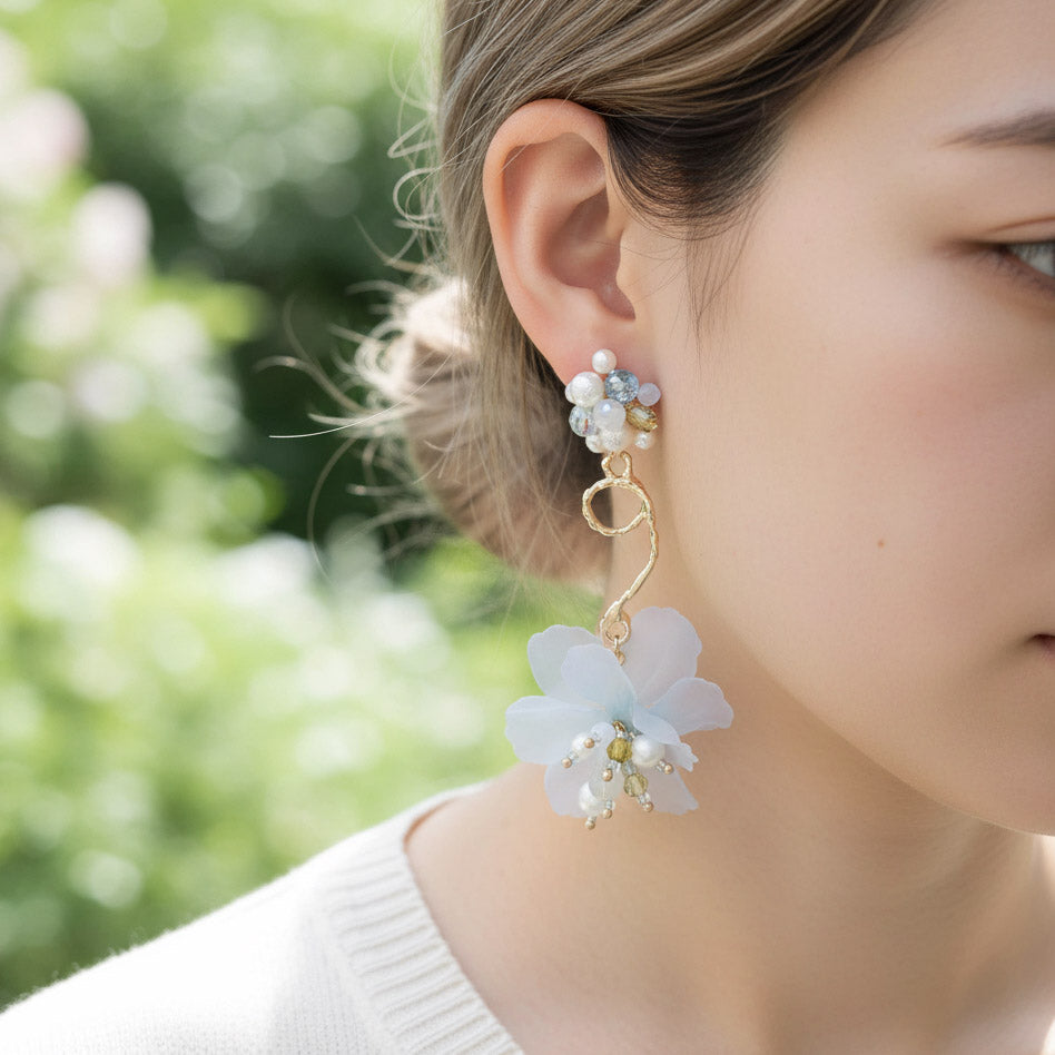 Close-up of a woman wearing floral earrings with a blurred green background
