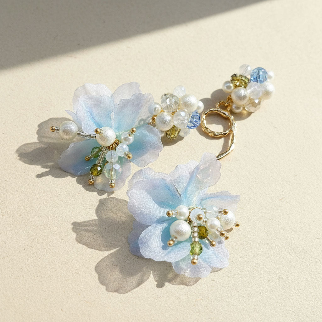 Pair of floral earrings with pearls and beads on a beige background