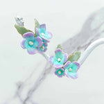 Pastel flower-shaped earrings on a white background