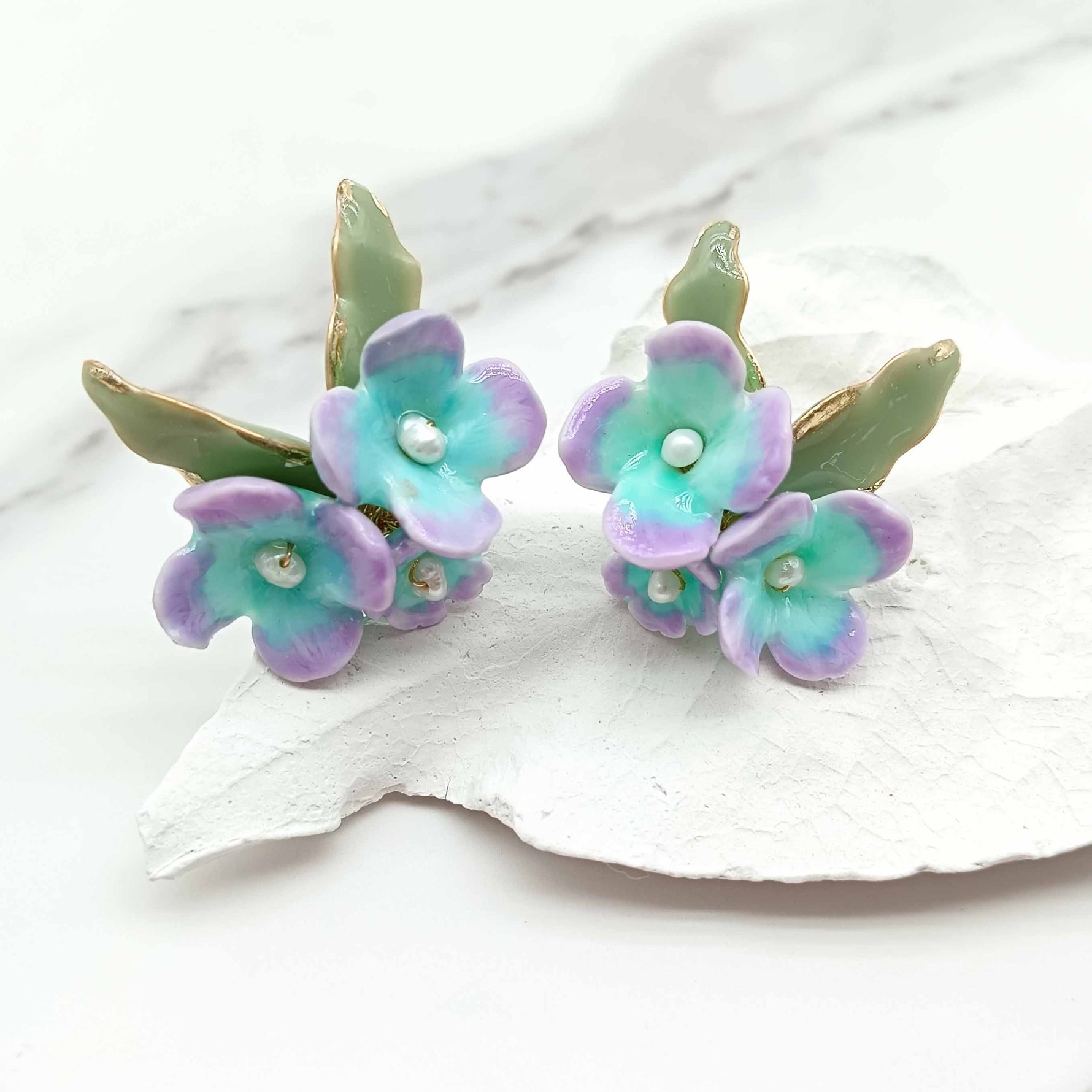Pair of floral earrings with pastel colors on a white surface