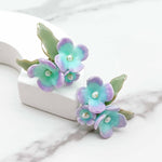 Pair of floral earrings with pastel colors on a marble surface