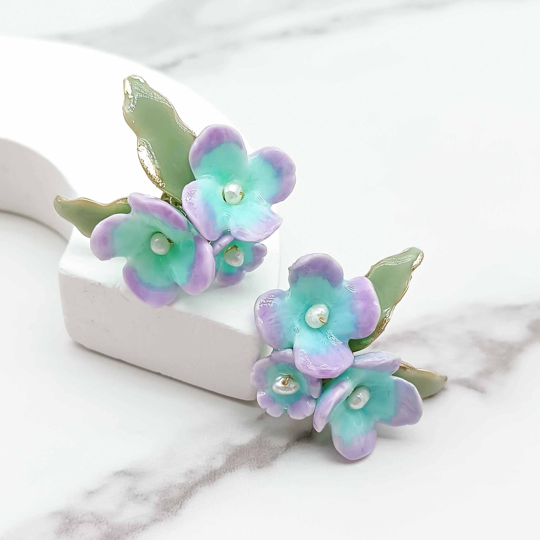 Pair of floral earrings with pastel colors on a marble surface