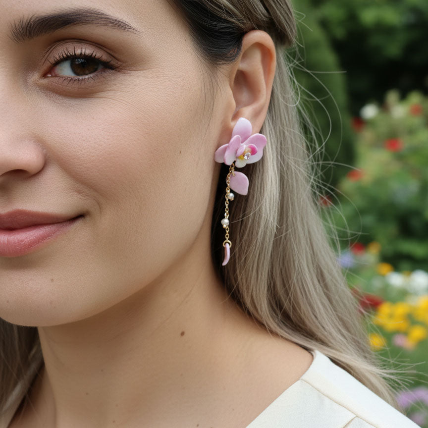 Close-up of a woman wearing pink floral earrings with a blurred garden background
