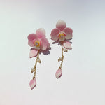 Pink floral earrings with gold accents on a light gray background