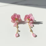 Pink floral earrings with pearl drops on a light background