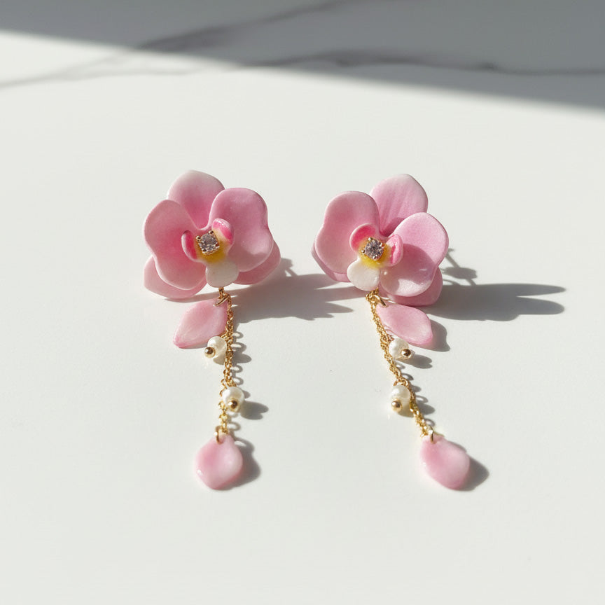 Pink floral earrings with pearl drops on a light background