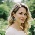 Model wearing blue tulip flower drop earrings with green leaves and crystal teardrop, handcrafted floral jewelry.