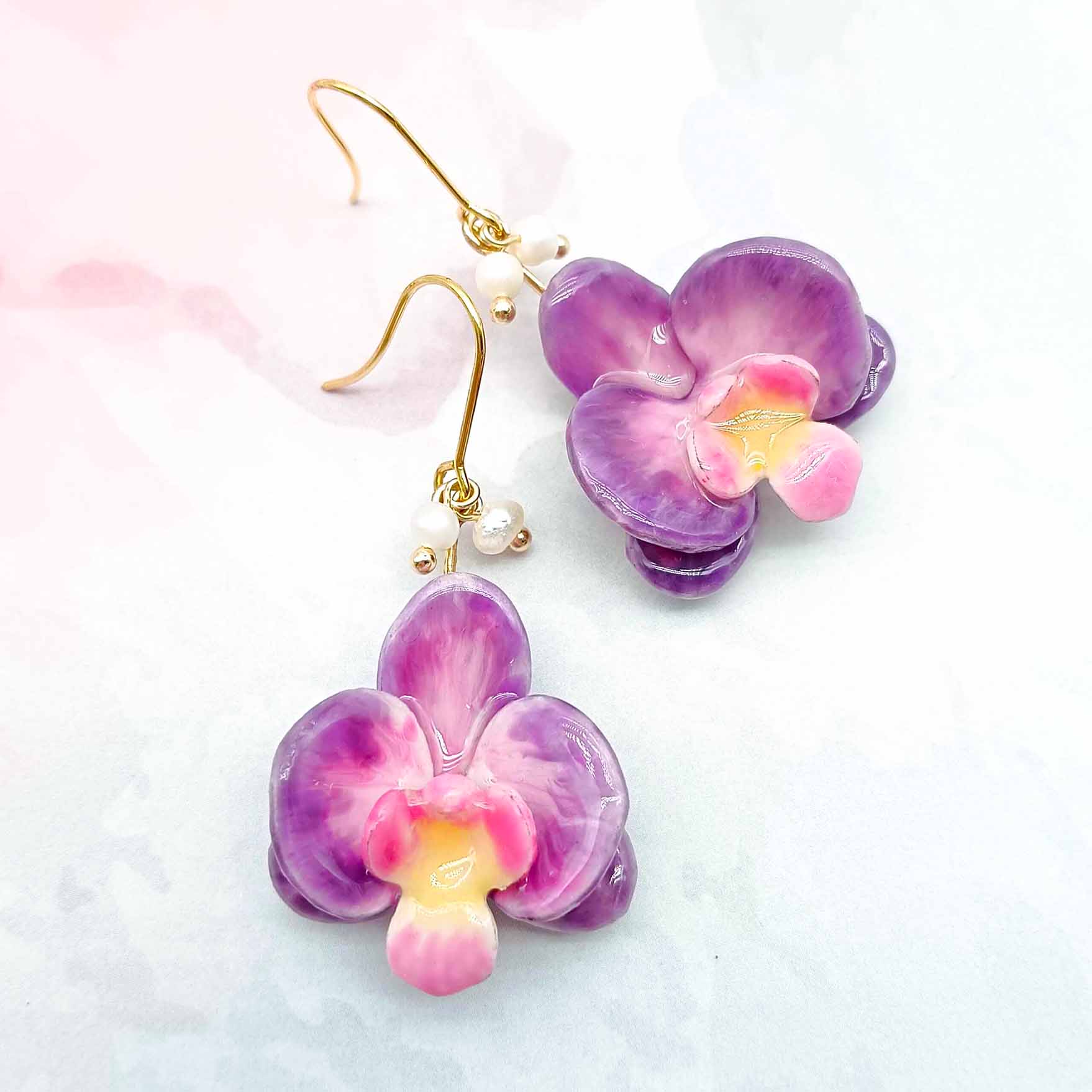 Purple and pink flower-shaped earrings on a light background