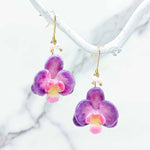 Purple and pink flower-shaped earrings on a white background