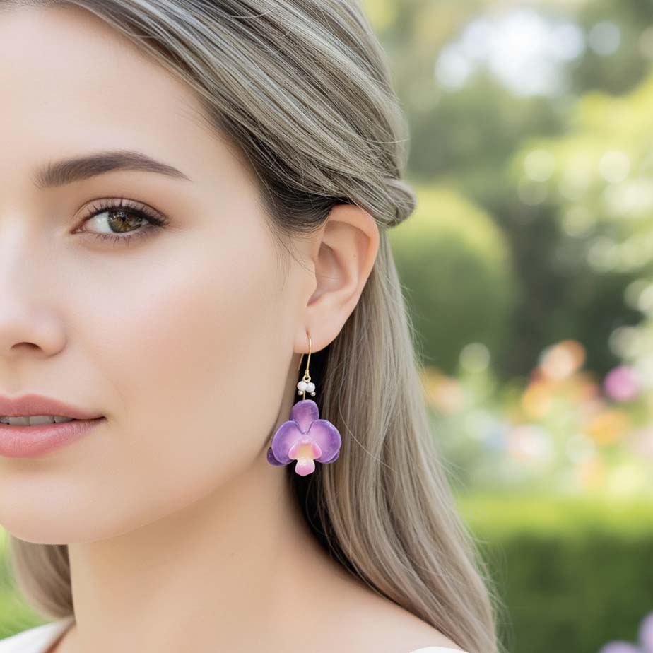 Woman wearing a purple flower earring outdoors with a blurred garden background