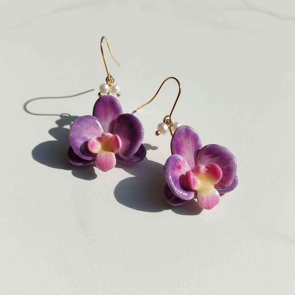 Purple flower-shaped earrings on a light gray background