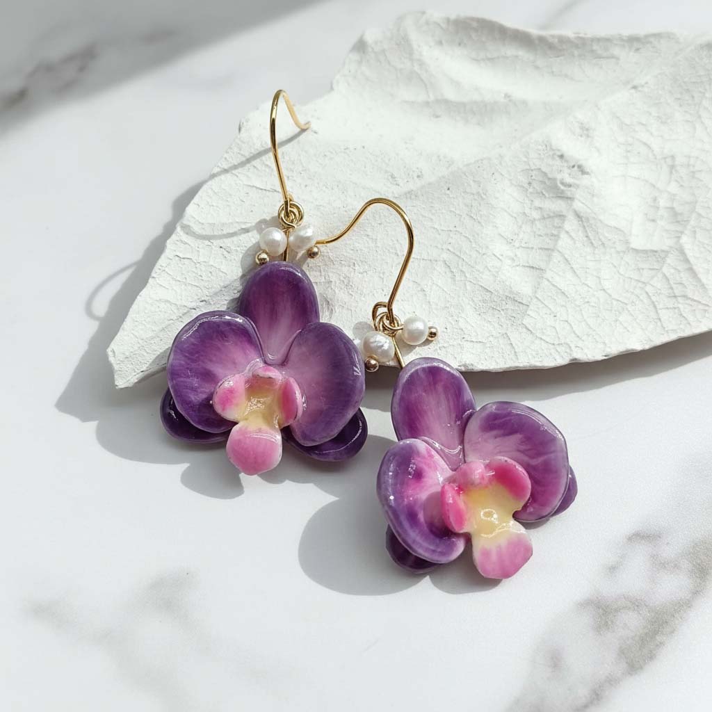Purple flower earrings with gold hooks on a white stone surface