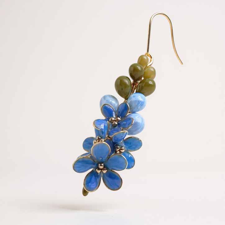 Blue floral earrings with green beads on a white background
