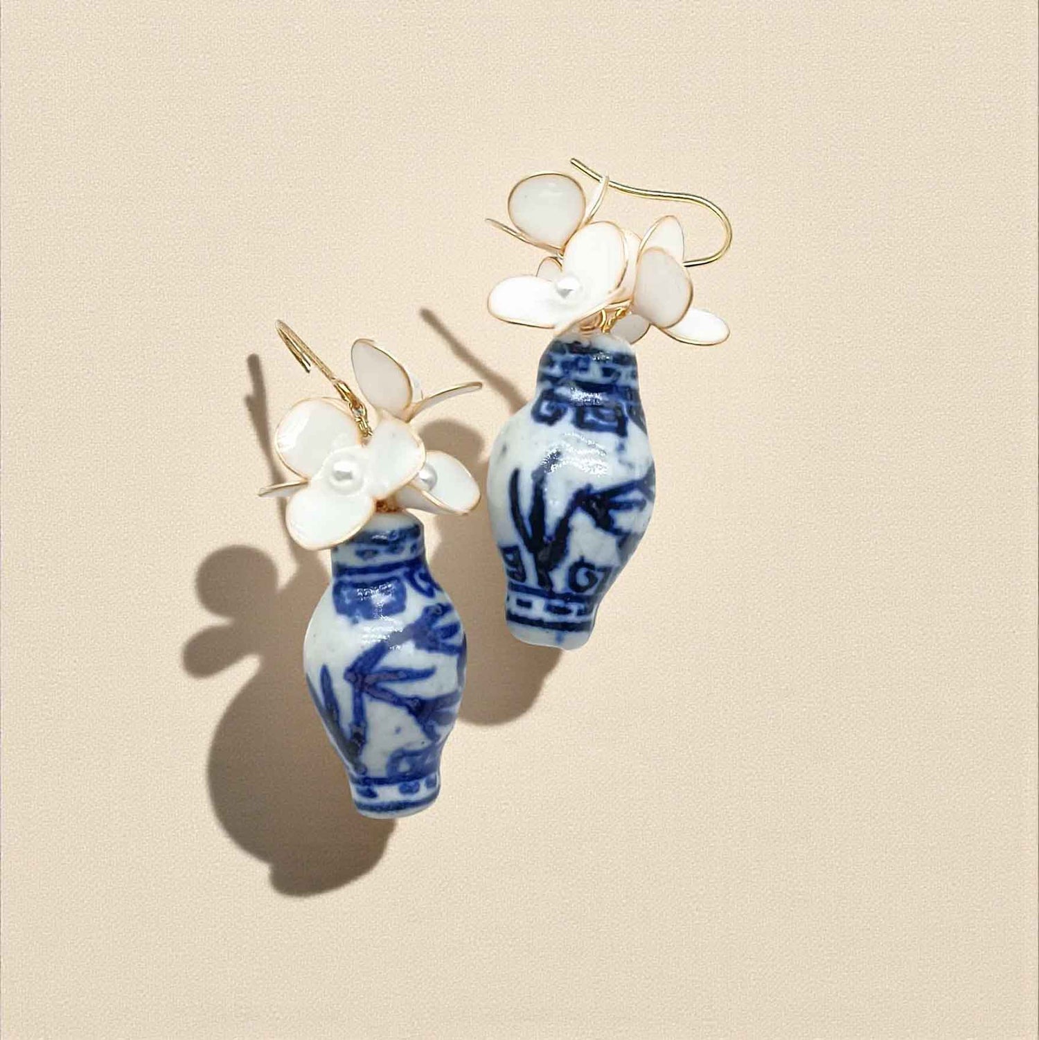 Earrings with blue and white floral designs on a beige background