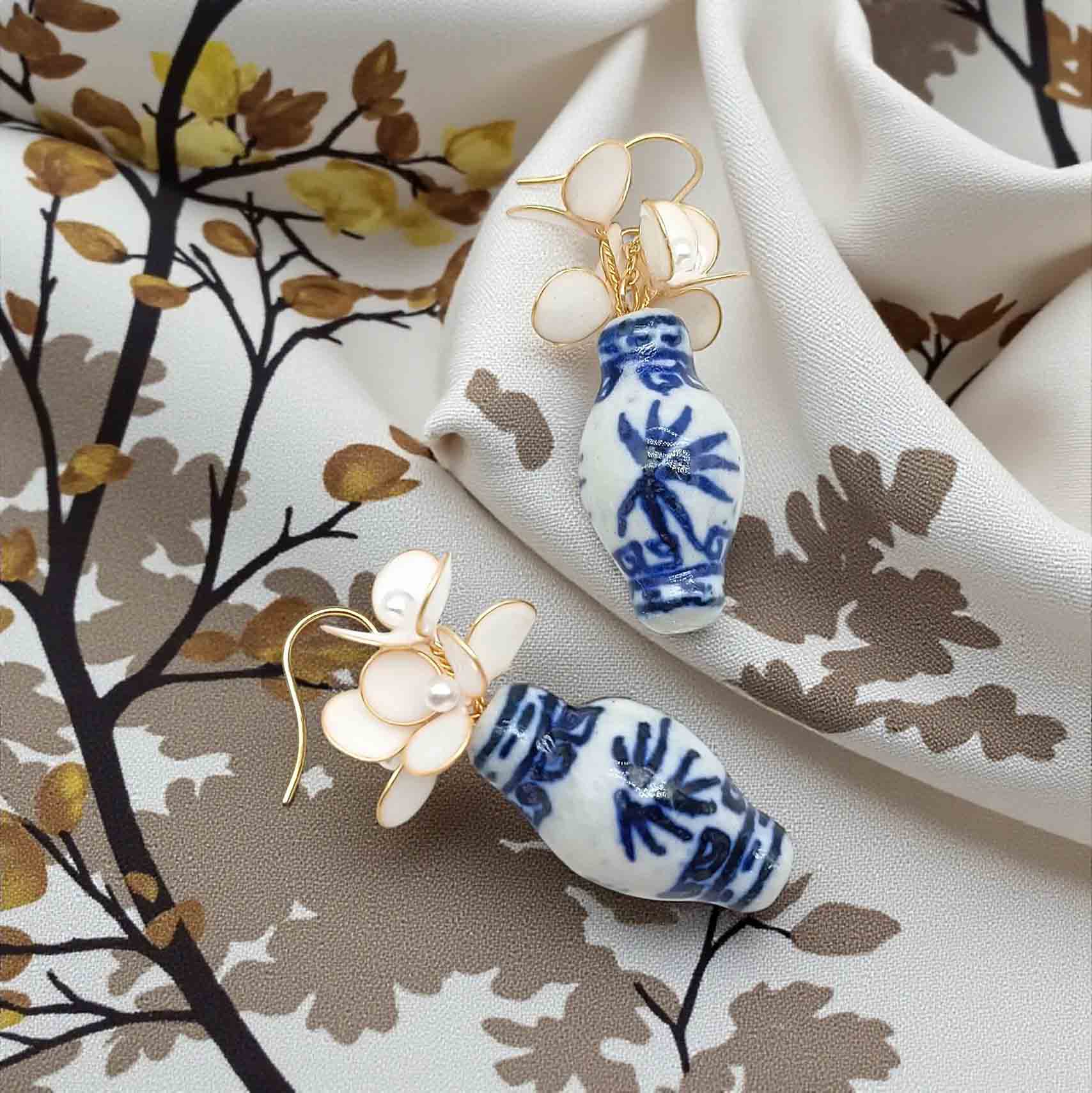 Pair of earrings with blue and white design on a floral fabric background