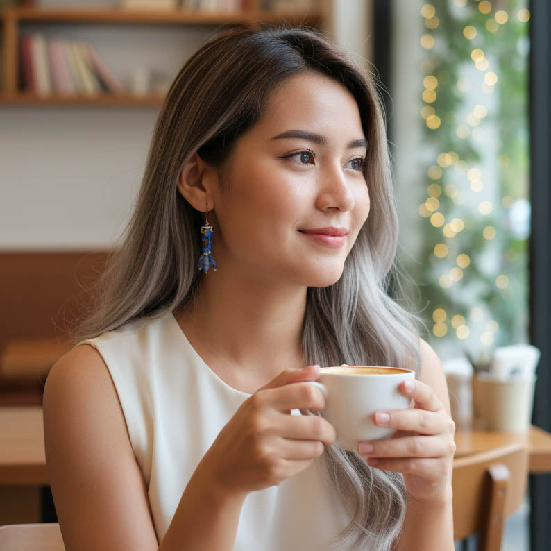 Woman holding a cup of coffee in a cozy indoor setting with blurred lights in the background