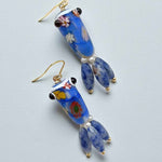 Pair of blue glass earrings with floral patterns on a light gray background