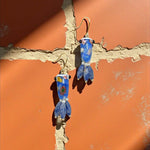 Blue glass earrings on a textured orange surface