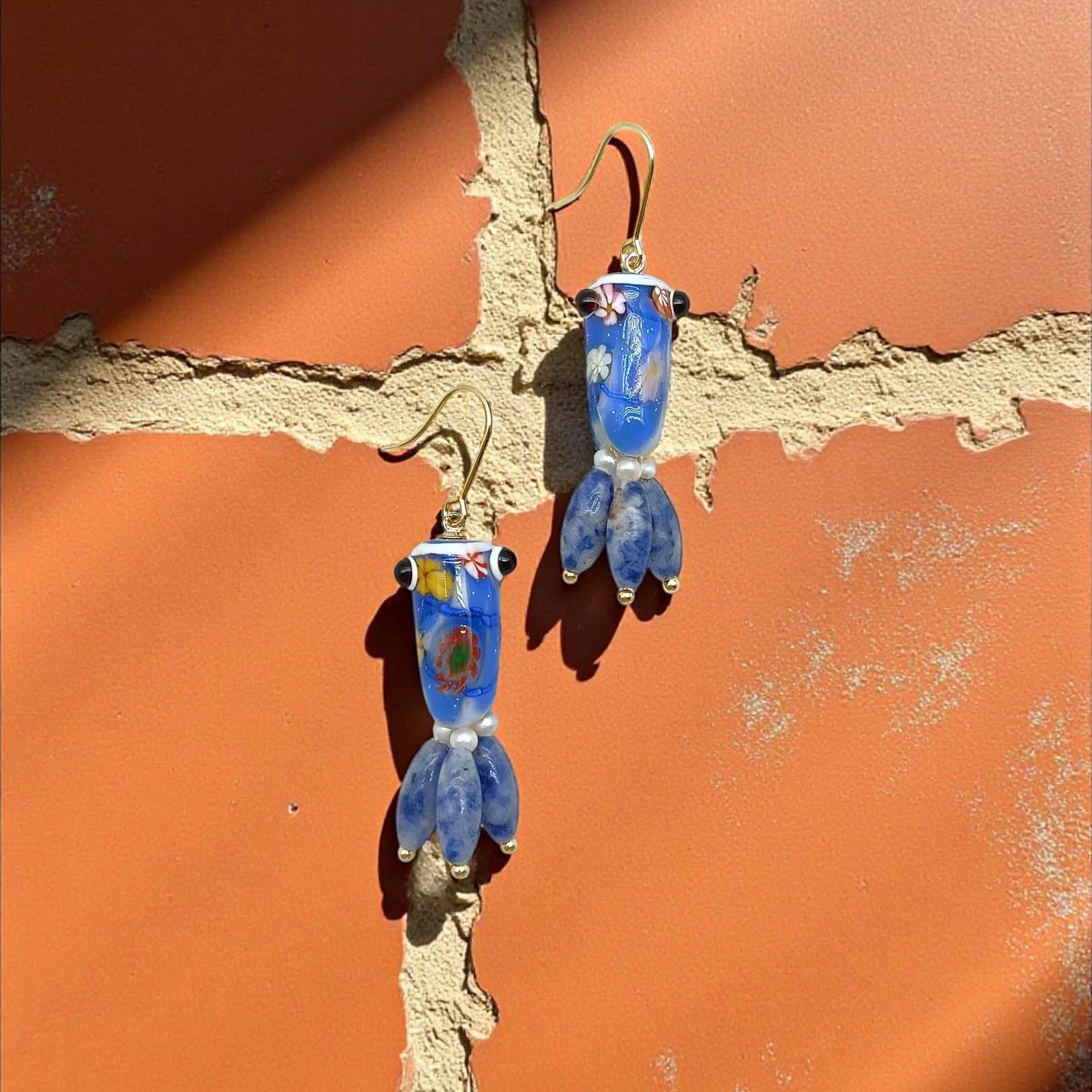 Blue glass earrings on a textured orange surface