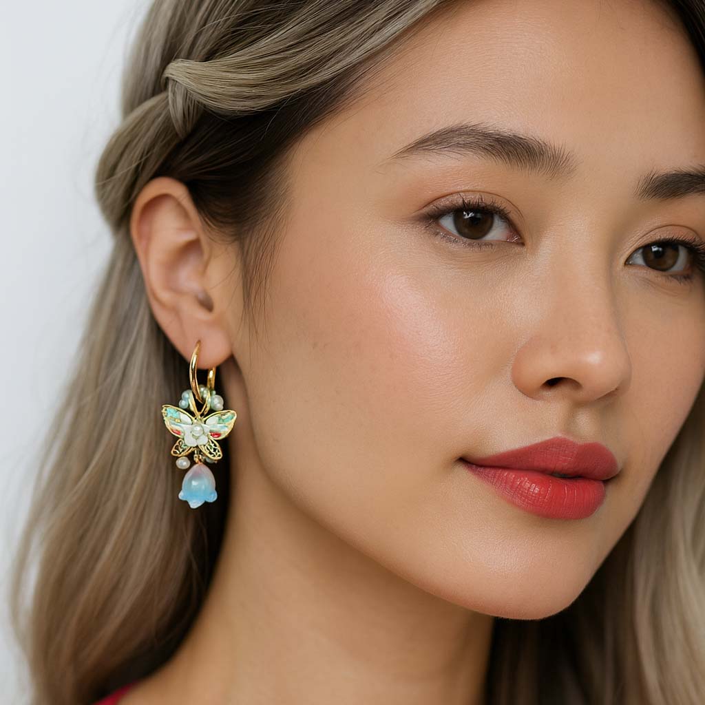 Close-up of a woman wearing butterfly earrings with a plain background