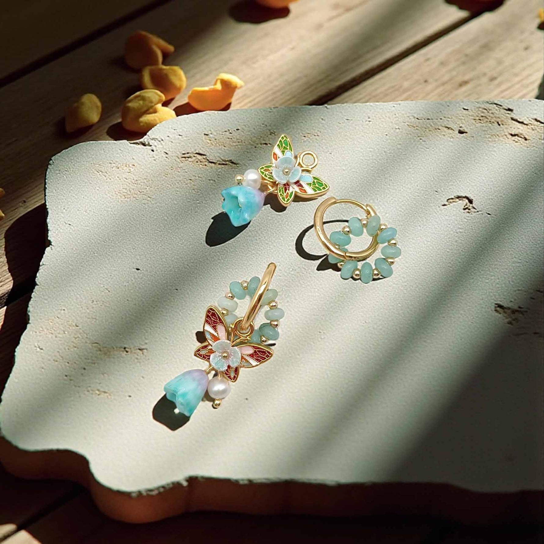 Pair of floral earrings with gemstones on a textured surface