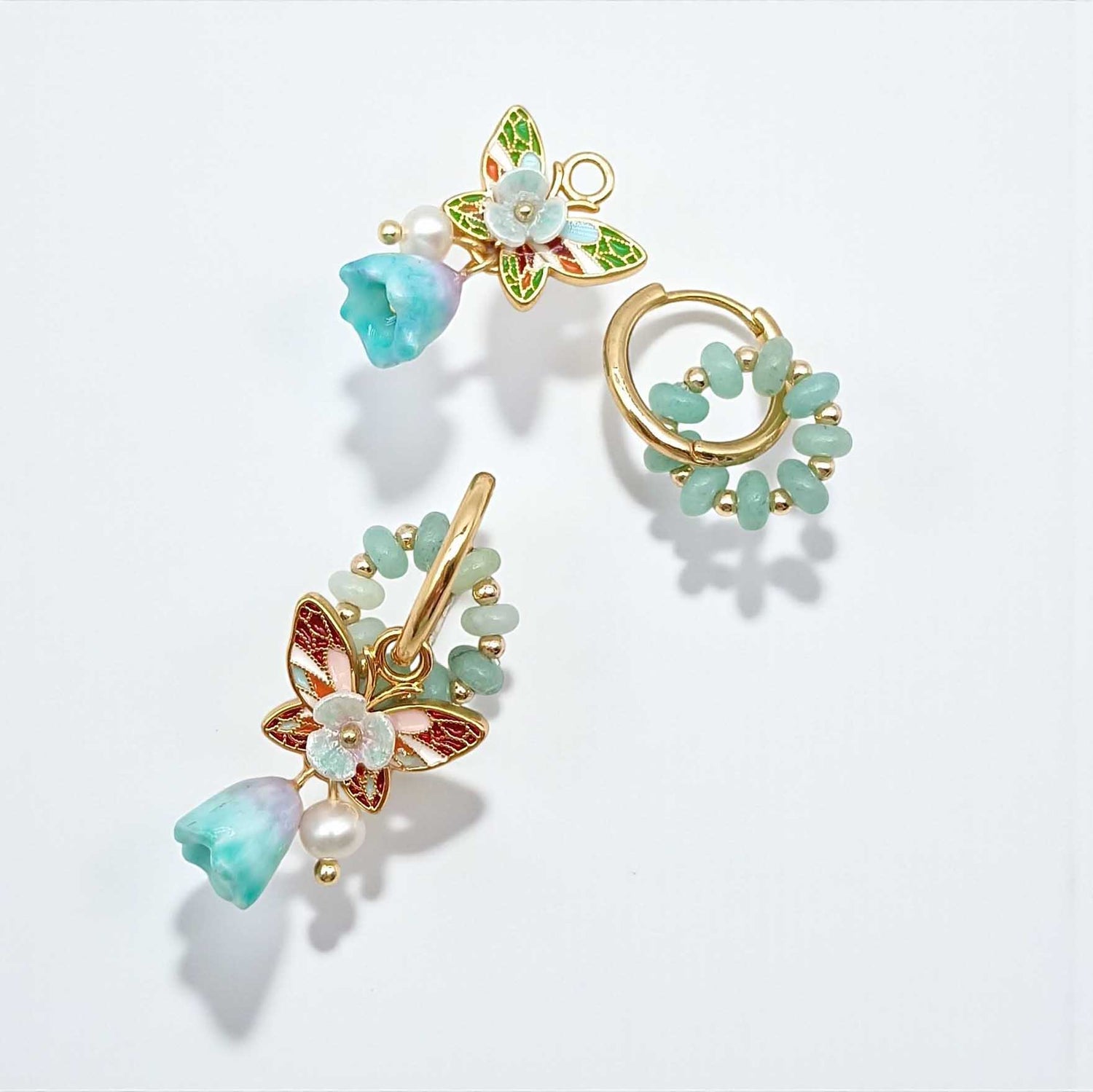 Pair of gold and turquoise butterfly earrings on a light gray background