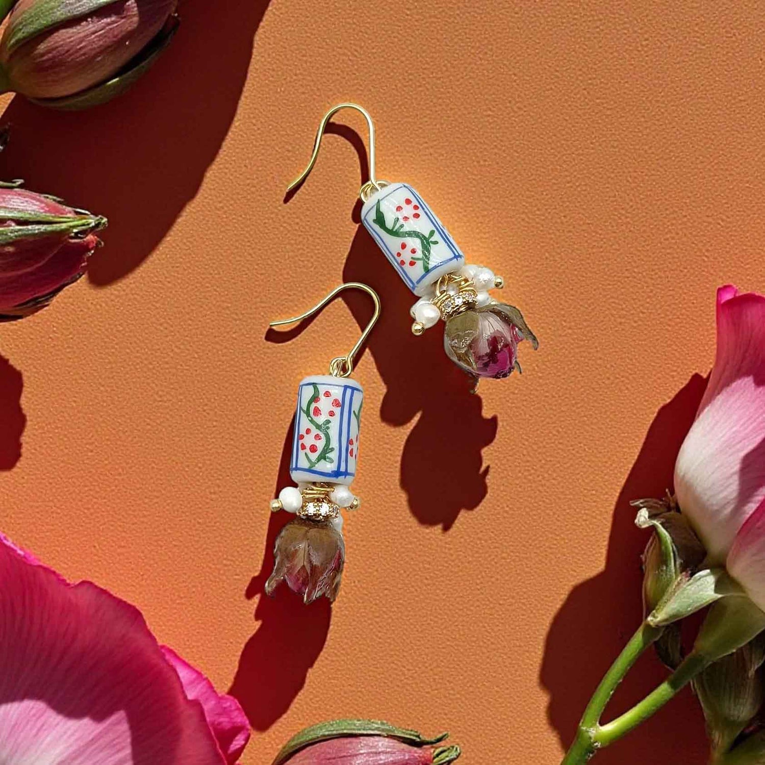 Decorative earrings with floral designs on a pink background