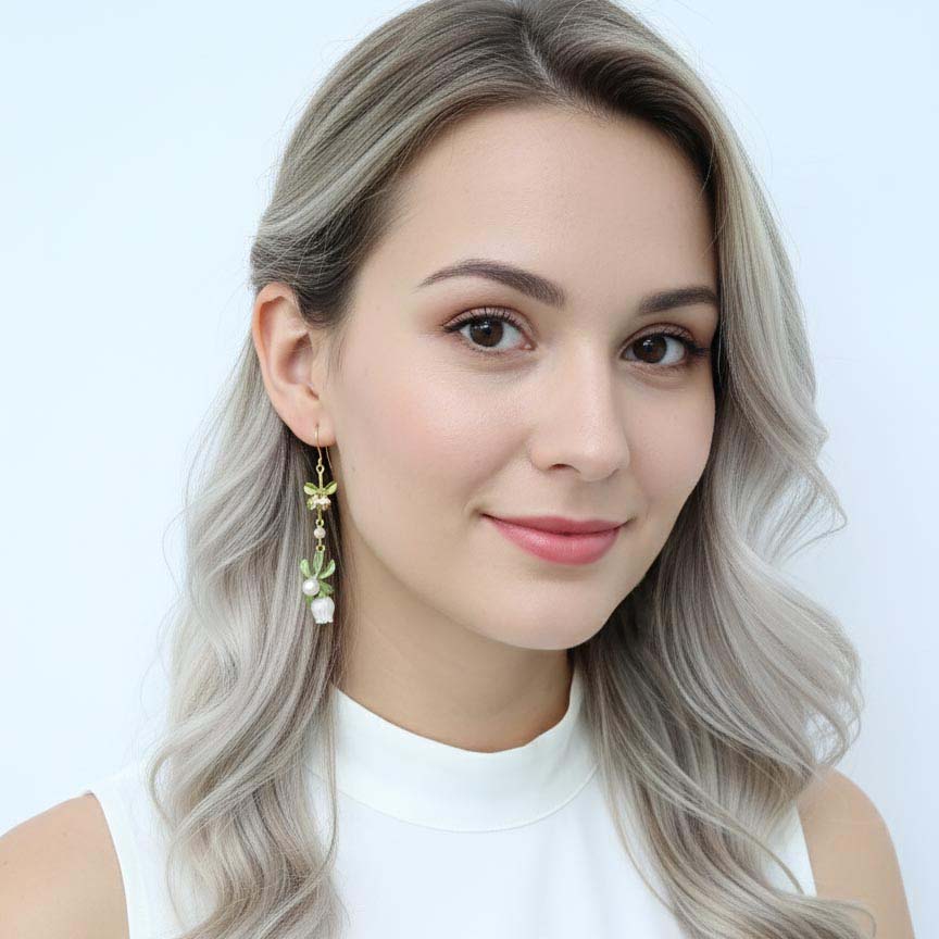 Woman with long, wavy hair wearing earrings against a light background
