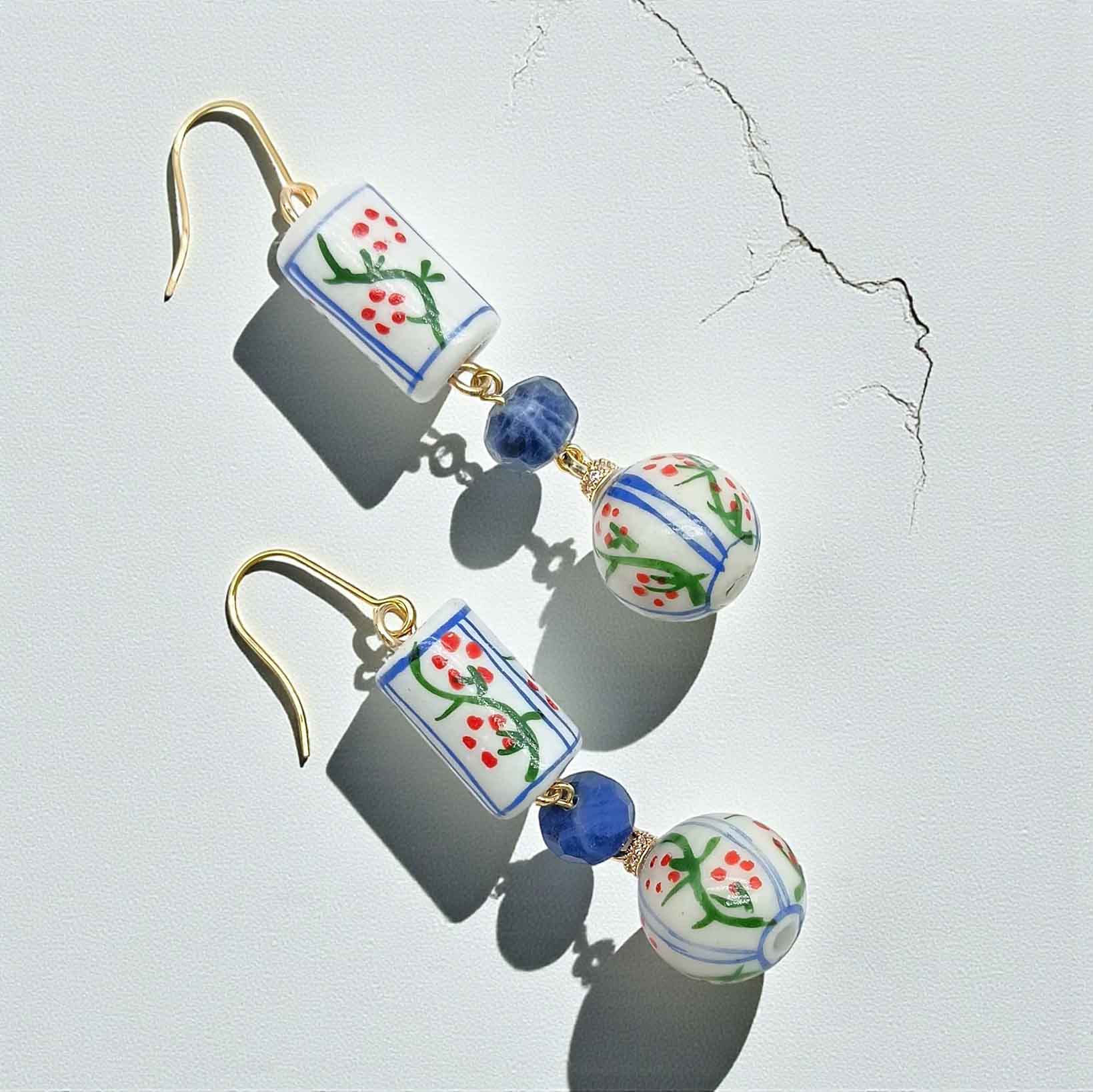 Pair of earrings with floral designs on a light gray background