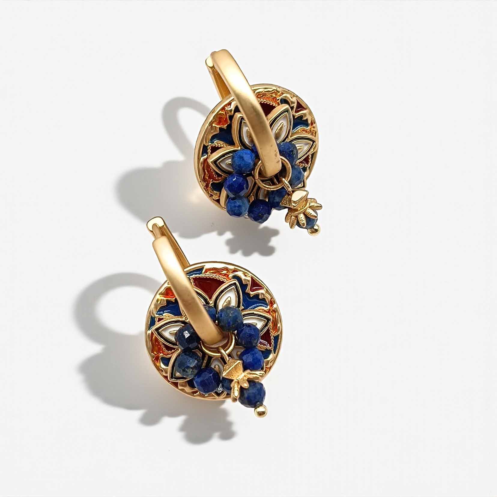 Gold earrings with blue stones on a white background