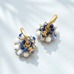 Pair of gold hoop earrings with blue and white stone accents on a light background