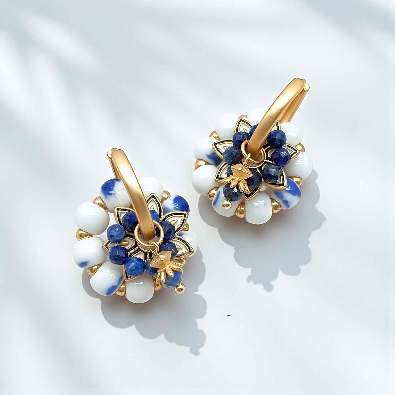 Pair of gold hoop earrings with blue and white stone accents on a light background