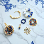 Collection of gold and blue jewelry pieces on a marble surface with floral patterns.