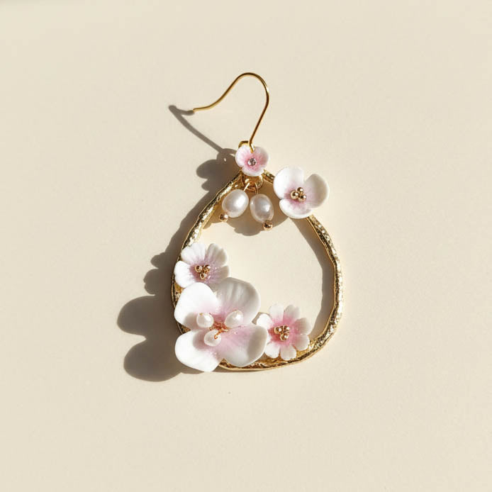Gold hoop earring with floral designs on a beige background