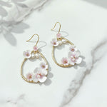 Pair of floral earrings with gold accents on a marble surface