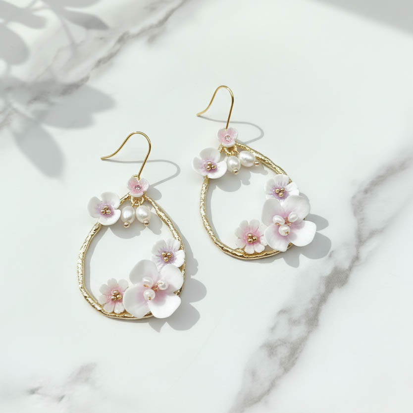 Pair of floral earrings with gold accents on a marble surface