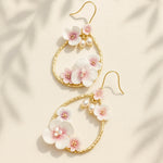 Floral earrings with gold hooks on a beige fabric background