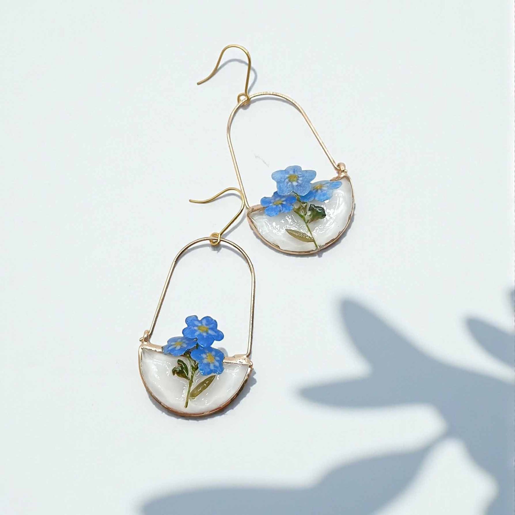 Pair of earrings with blue flowers on a light background