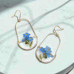 Pair of earrings with blue flowers on a light background