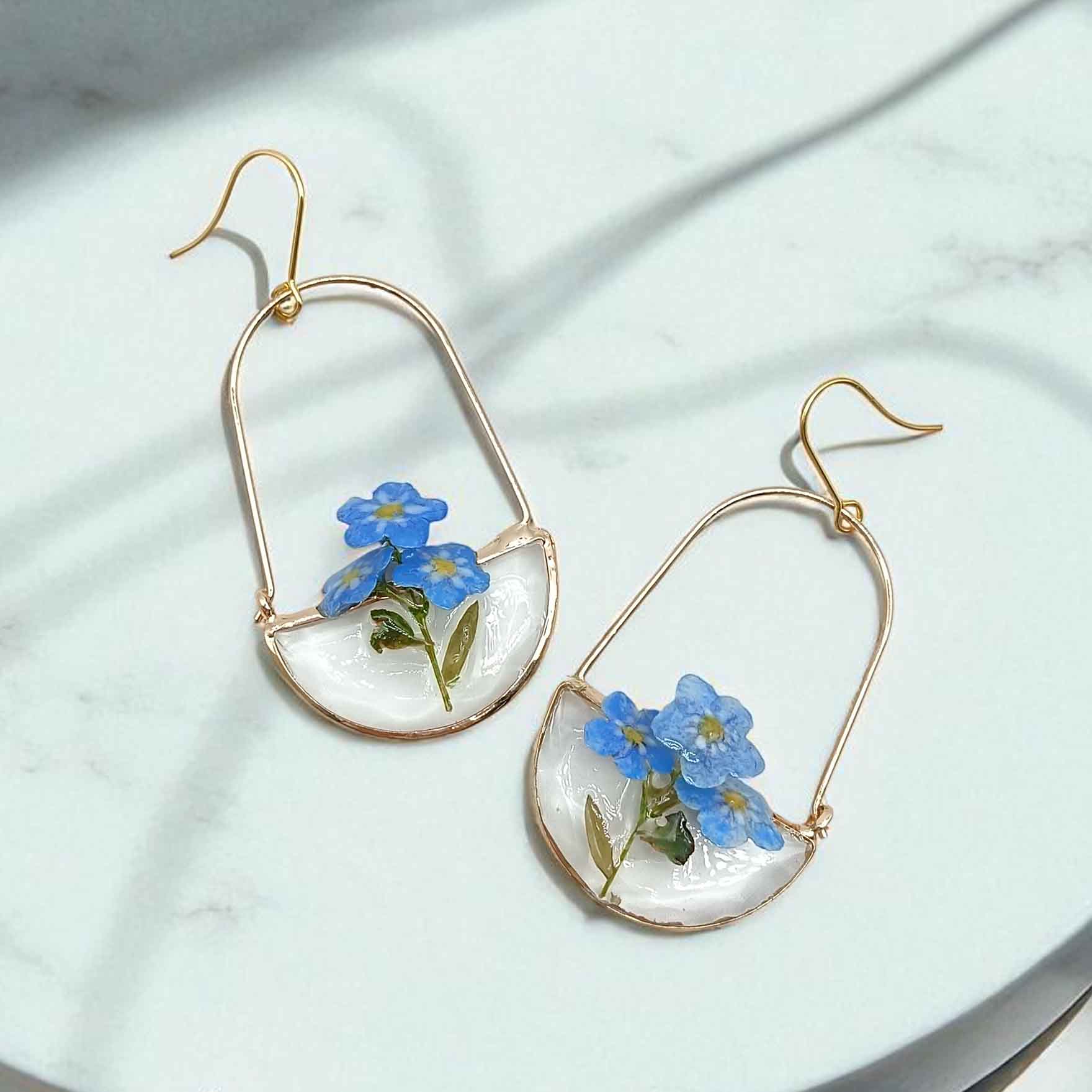 Pair of earrings with blue flowers on a light background
