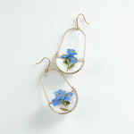 Gold hoop earrings with blue flowers on a white background