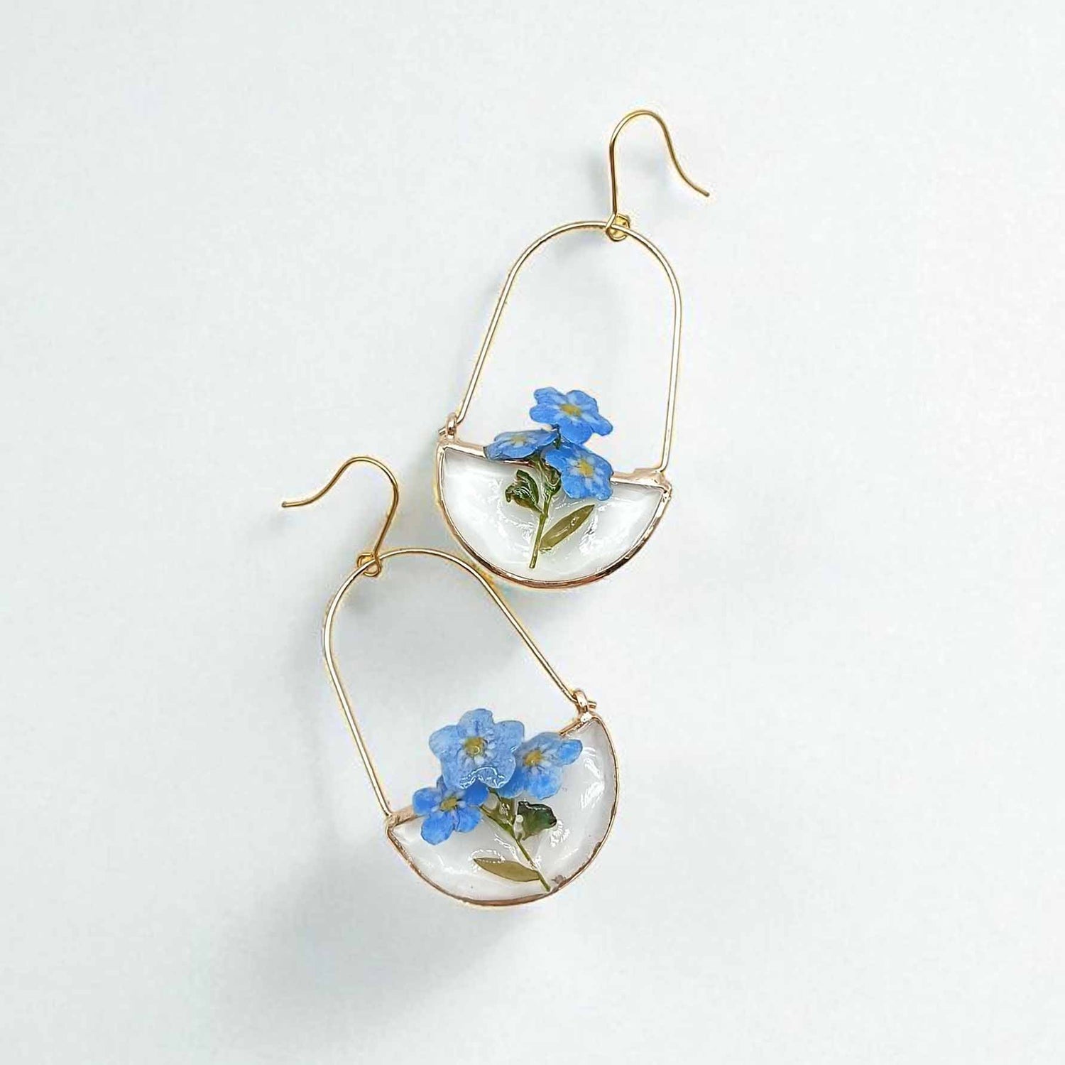 Gold hoop earrings with blue flowers on a white background