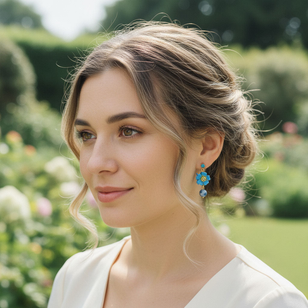 Model wearing handcrafted blue daisy flower earrings in garden setting.