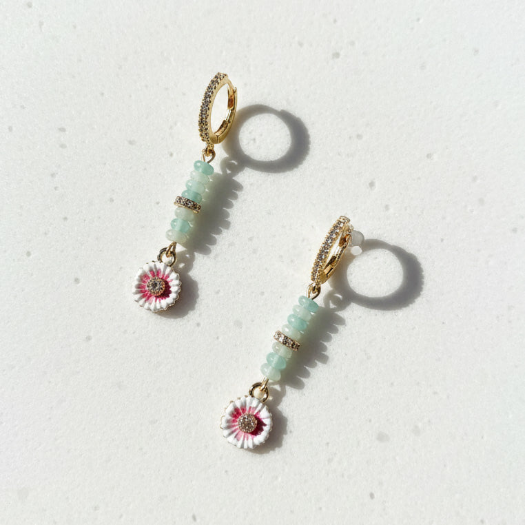 Close-up of gold-plated amazonite and enamel flower earrings under natural light.