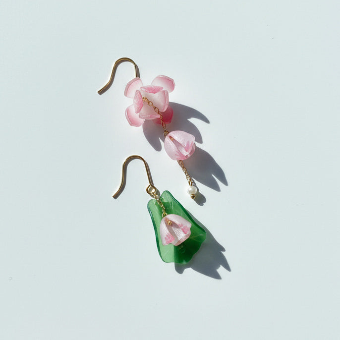Handcrafted resin floral earrings in pink and green with pearl detail on white background.