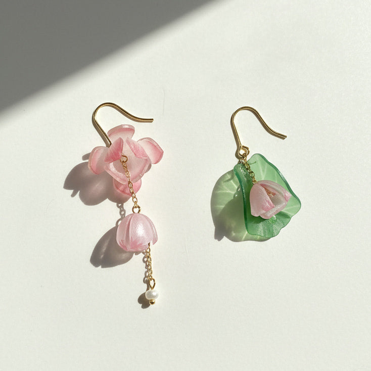 Asymmetrical resin flower earrings with freshwater pearls under sunlight.