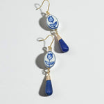 Pair of earrings with blue and white floral design on a light gray background